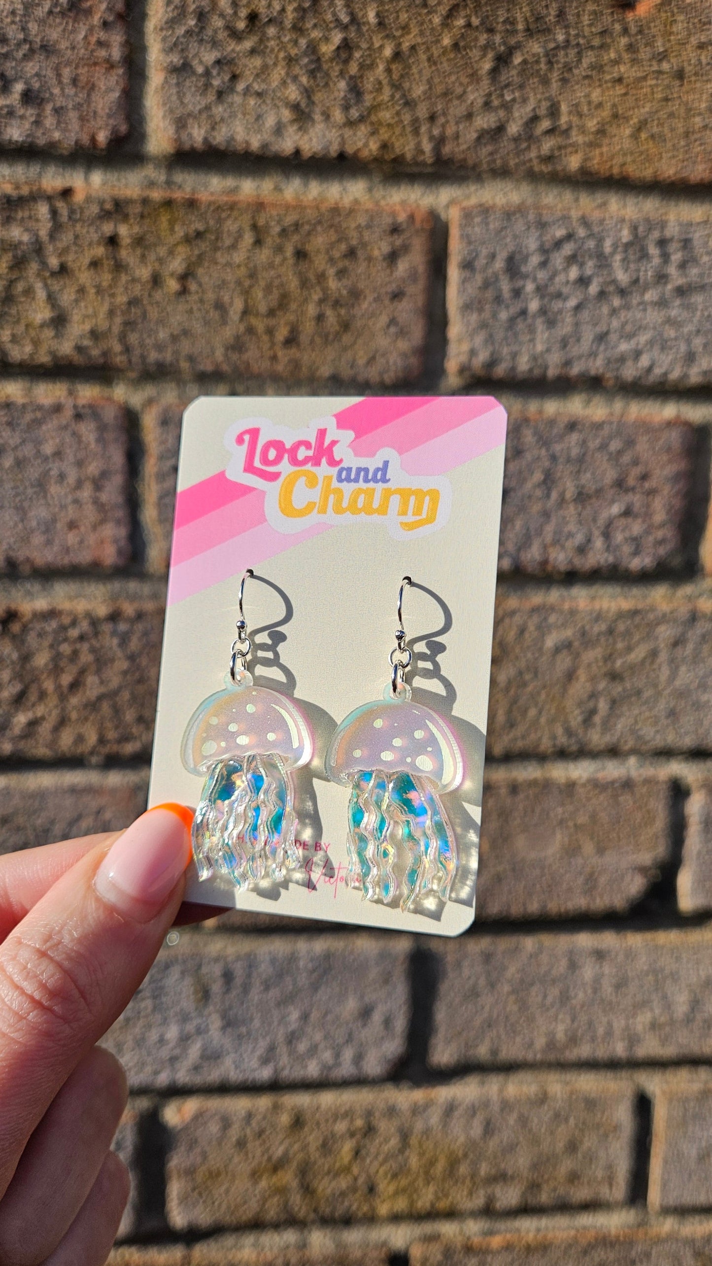 Earring packaging with a hand holding it against a textured wall background